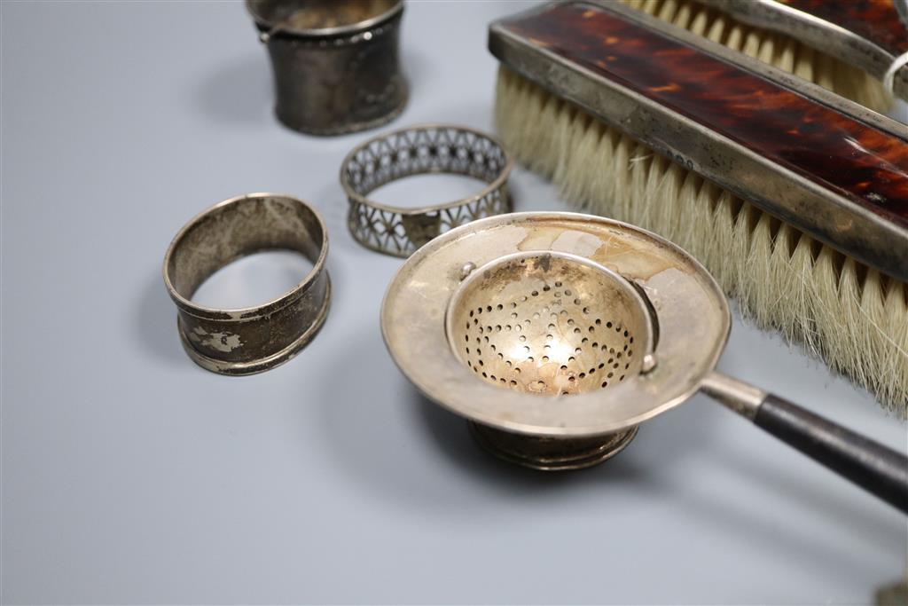 A silver mustard pot, silver sauceboat, three silver and one sterling napkin ring, two silver tea strainers etc.